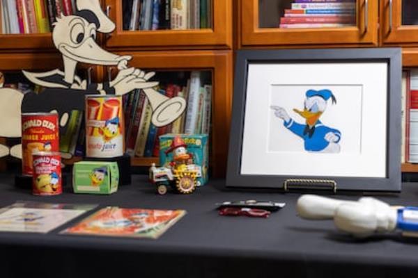 Some Donald Duck objects preserved in the Walt Disney Studios archives, such as prints of the character, toys, tomato and orange juices, and posters.