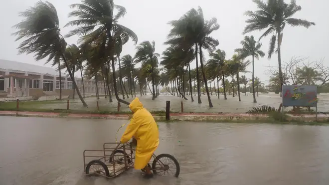 A person rides his bike through a flooded street in the rain as Hurricane Milton passes off the coast of Progreso, Yucatan state, Mexico